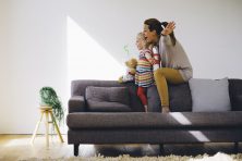 Mother and daughter are playing pretend on the sofa on the sofa in their living room.