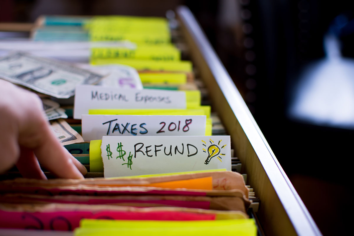 tax forms in filing cabinet and words refund and taxes 2018 written on file folders