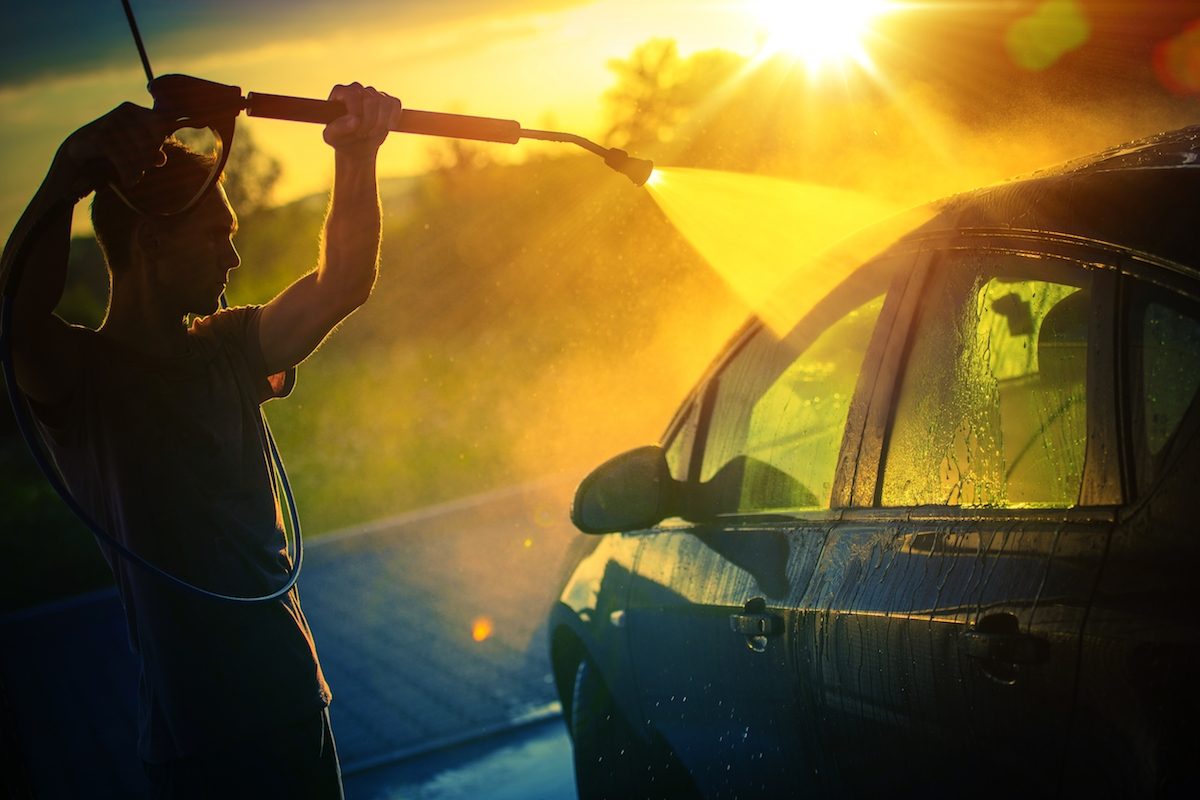 Man washes car at sunset