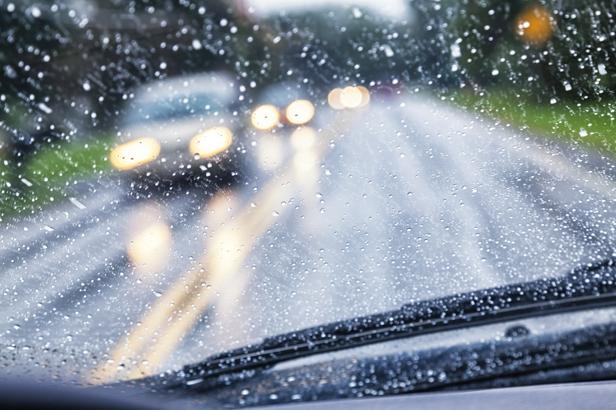 Driver point of view looking through a wet windshield while driving.