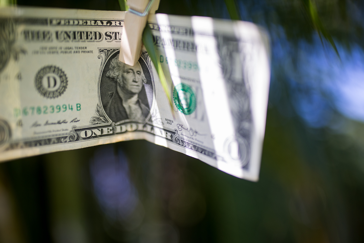 A dollar bill hanging from a clothes line.