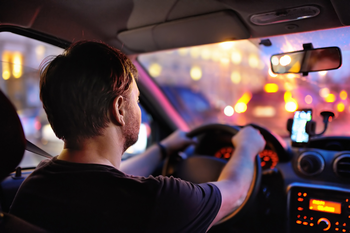 Male driving a car during evening traffic jam.
