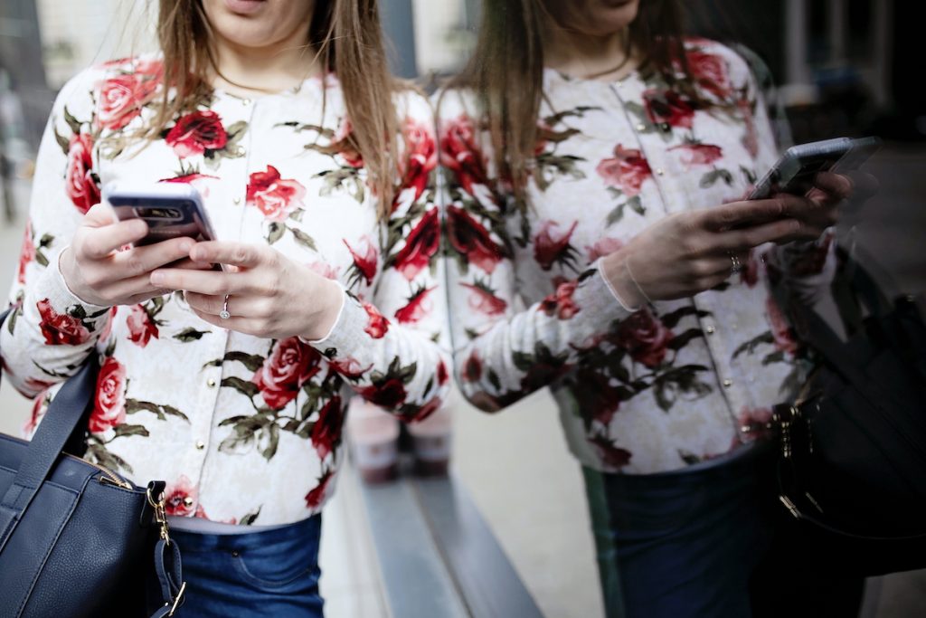 A woman holds her purse and looks at her phone.