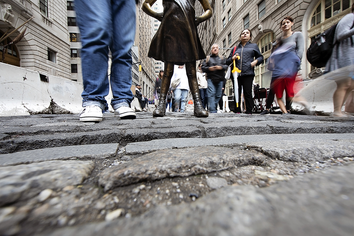 people passing statue on wall st.