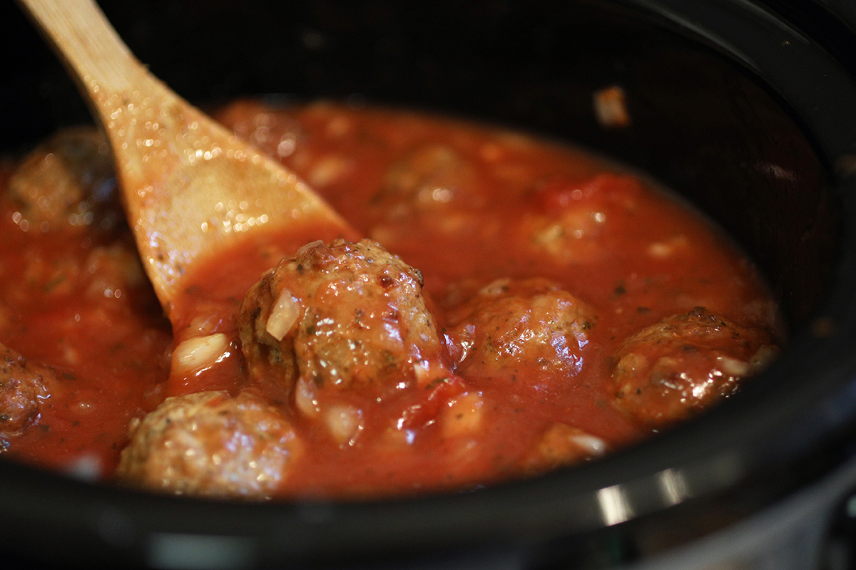 Meatballs are added to the sauce as spaghetti and meatballs are made in a crockpot.