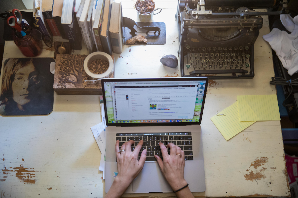 Woman's hand working on a laptop on her desk.