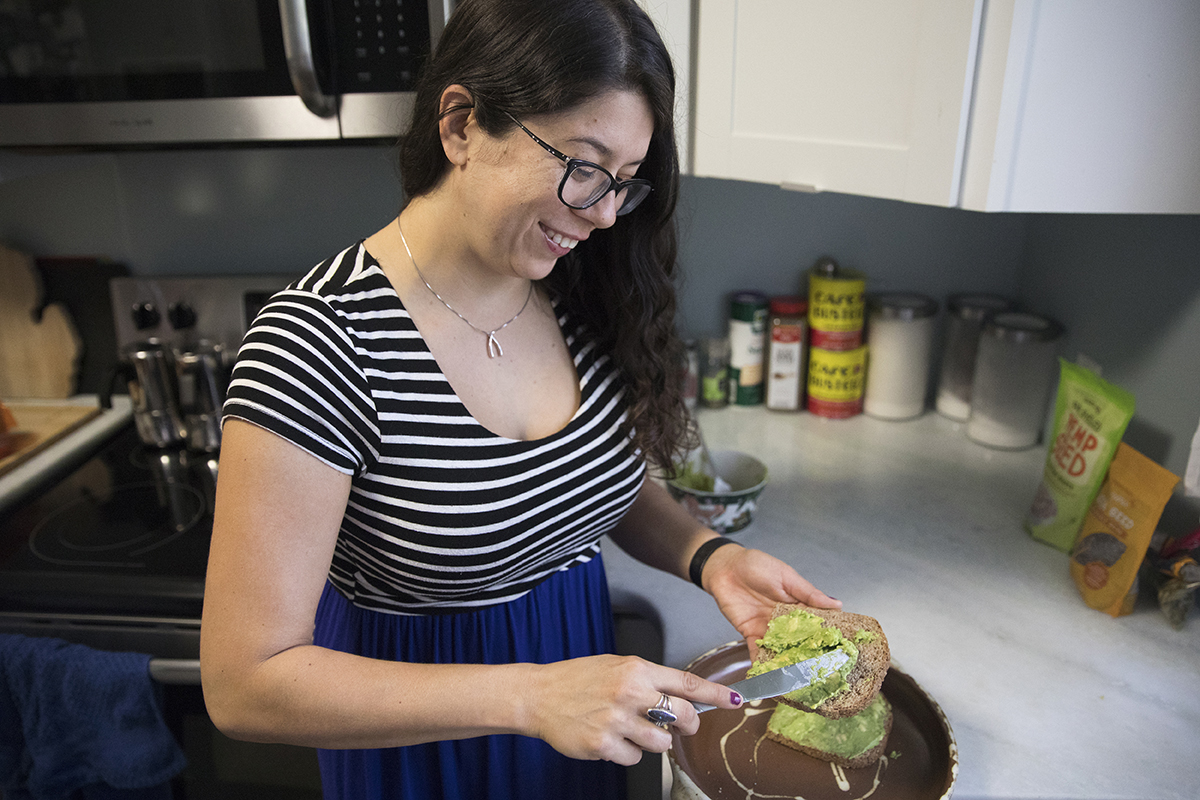 A woman makes avocado toast in her home.