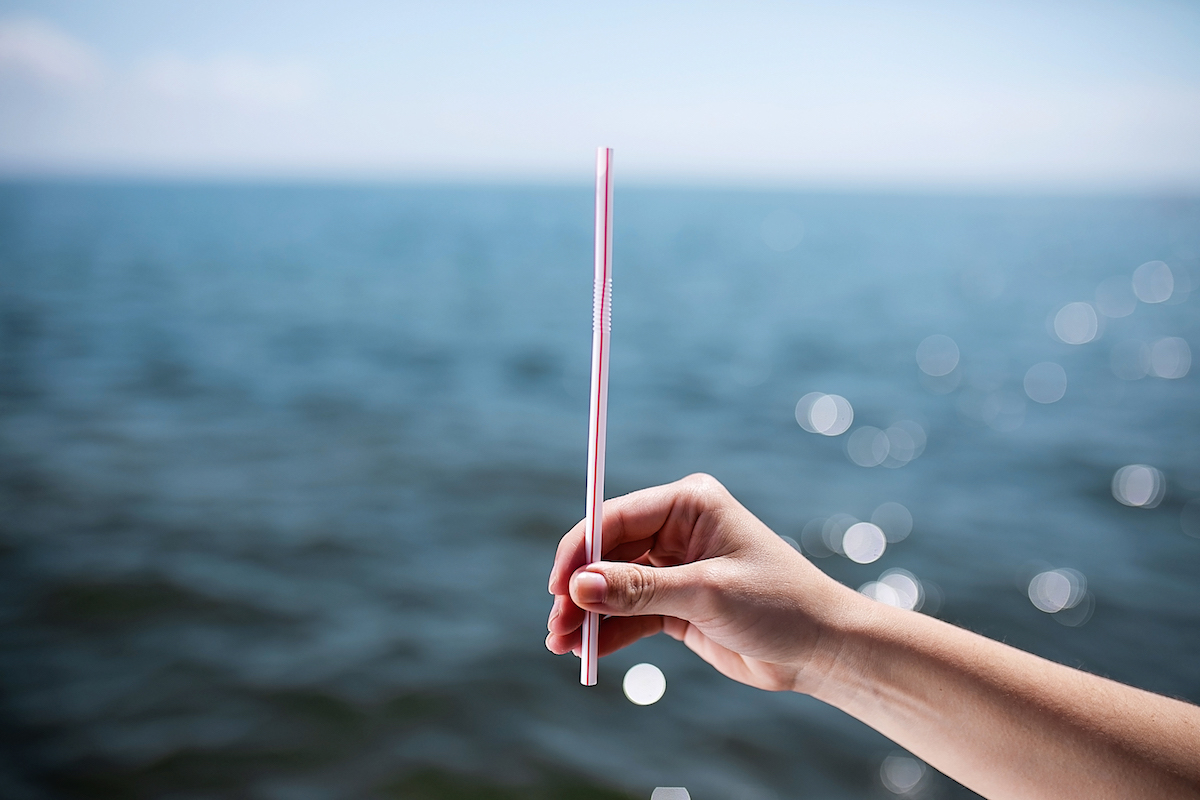 a hand holding out a plastic straw