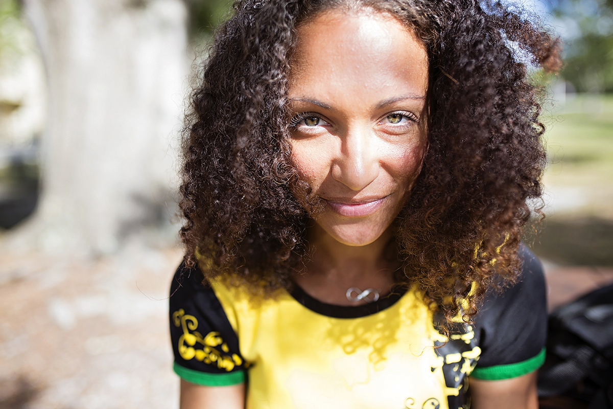 A woman with curly hair looks at the camera.