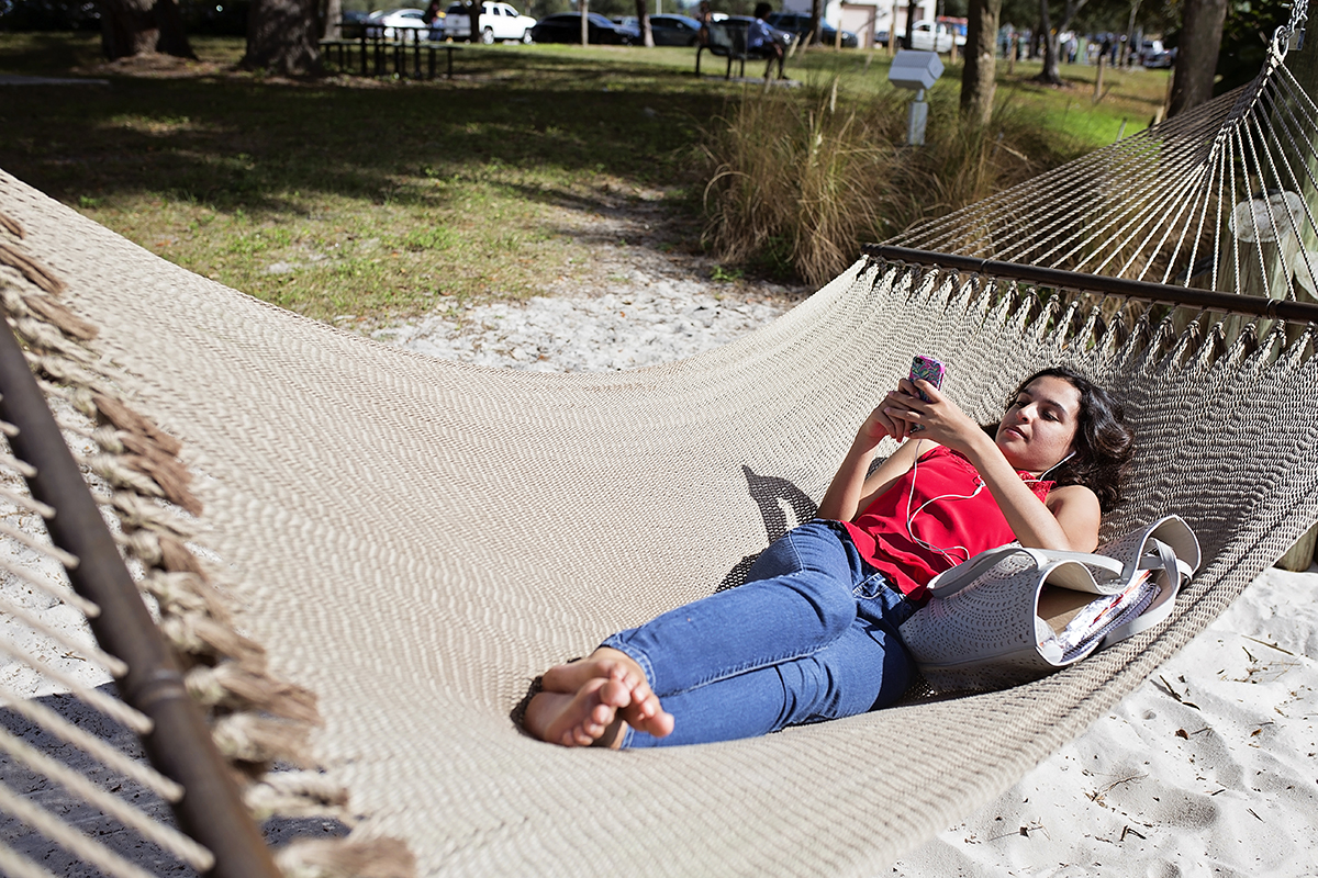A woman relaxes on a hammock on a college campus.