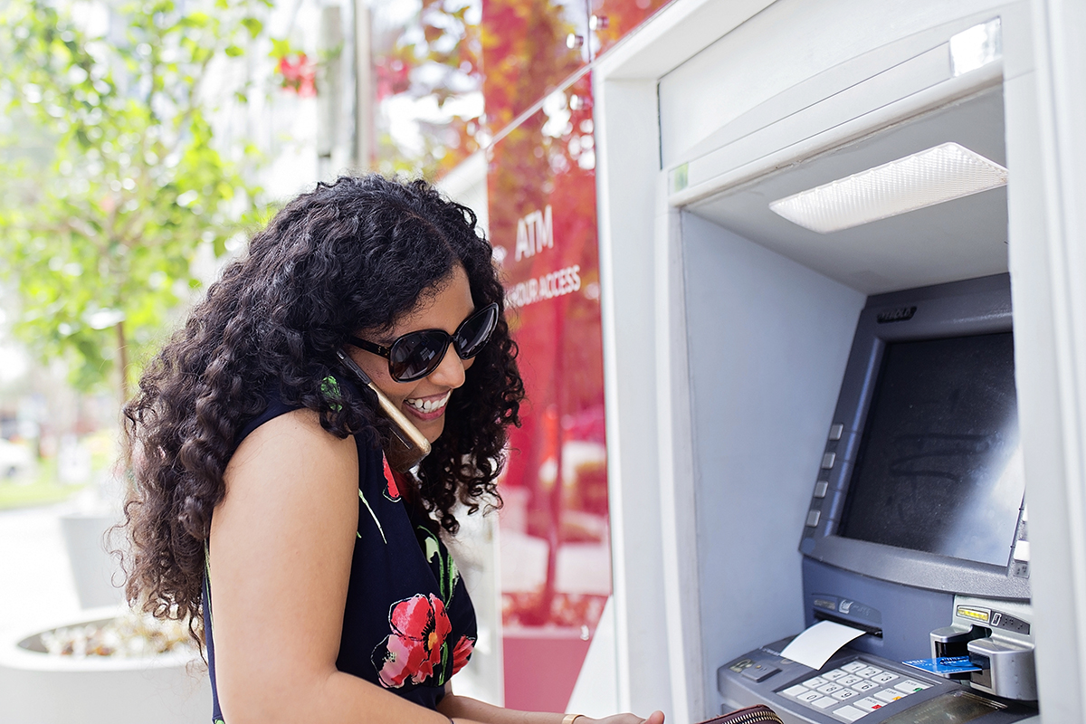 A woman smiles as she pulls money out of her bank account.