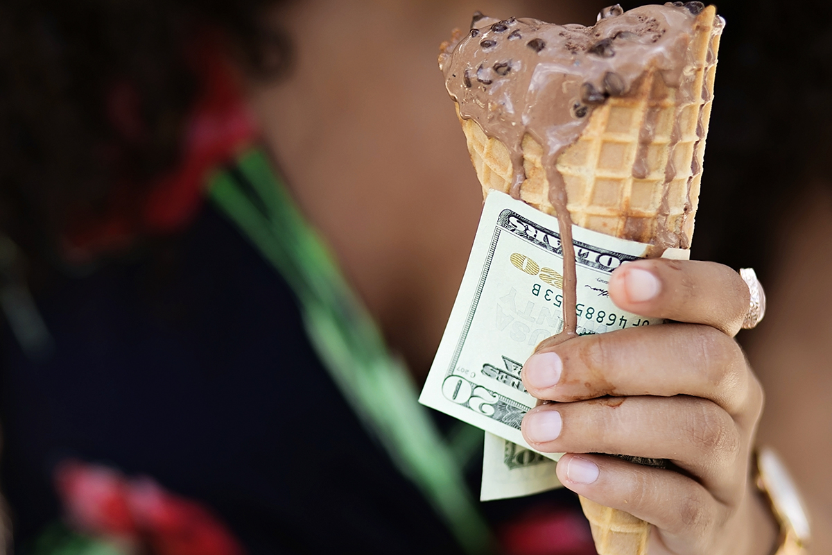 A woman eats gelato with the money she pulled out of her bank account,