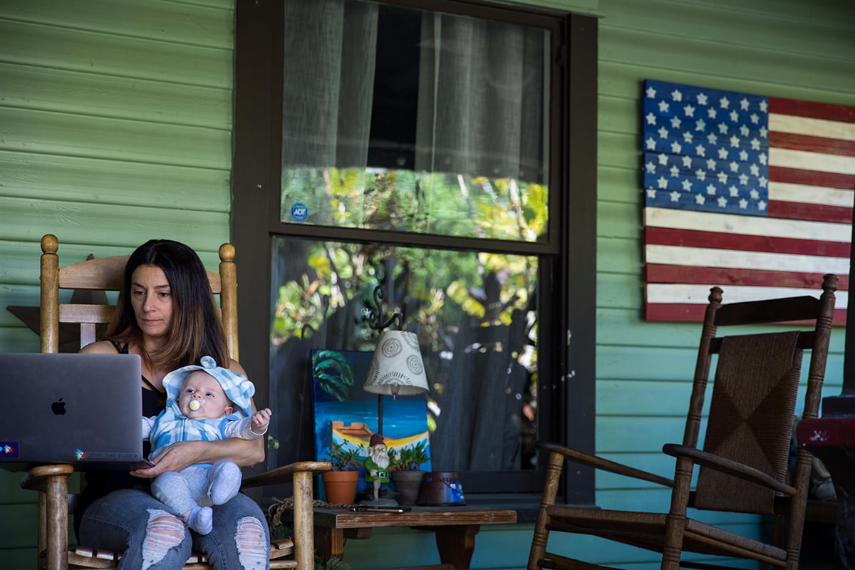 Woman works at home while holding son