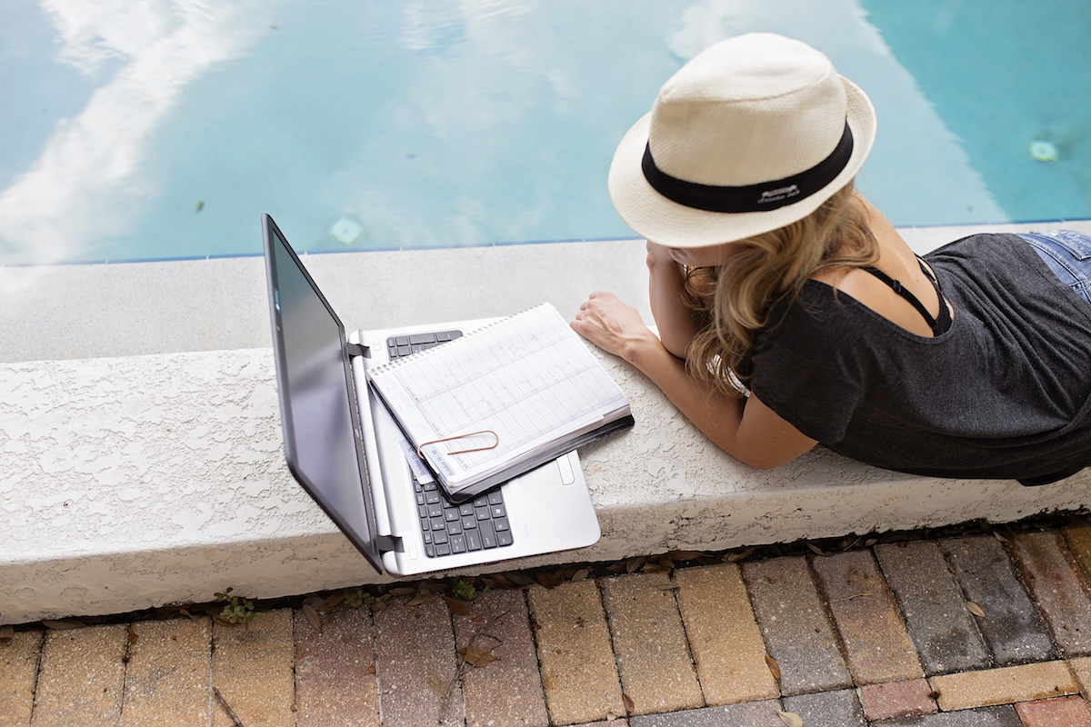 girl working on computer by the pool