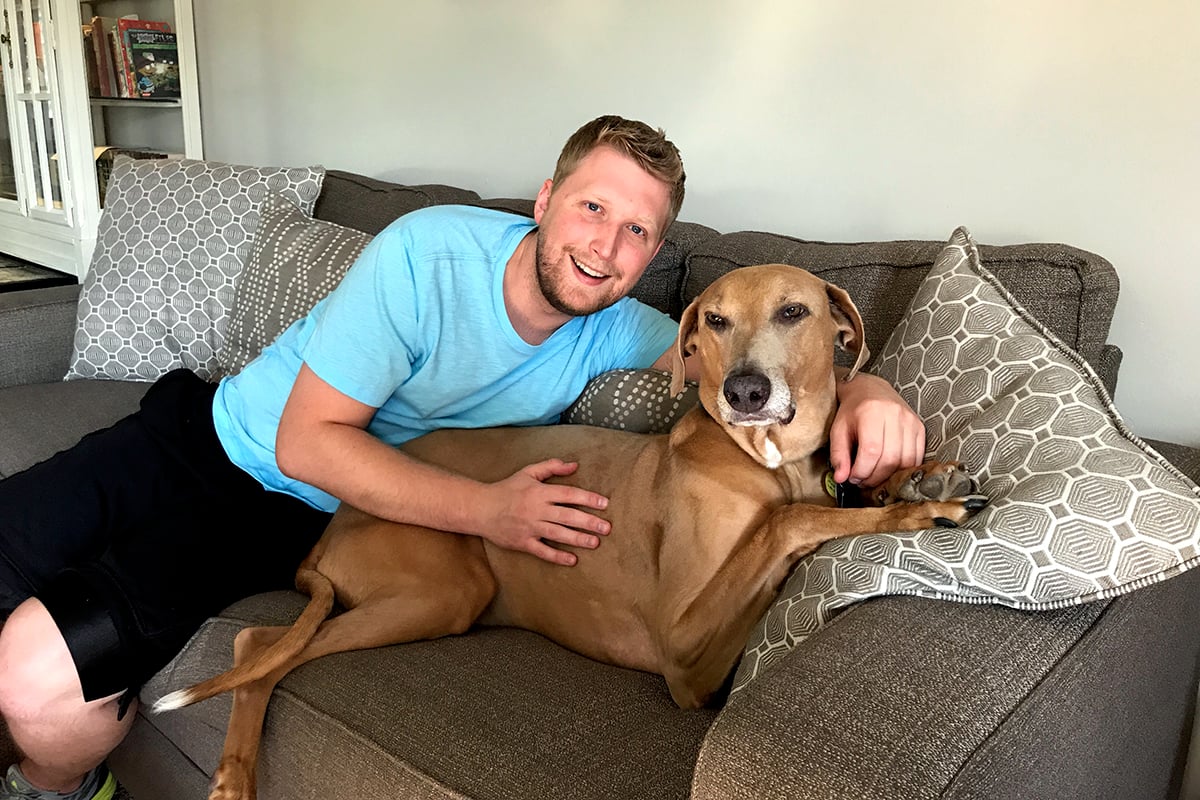 man sitting on couch with dog