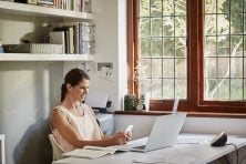 Smiling woman with mobile phone at table in house