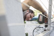 A man fixes the side railing of a house.