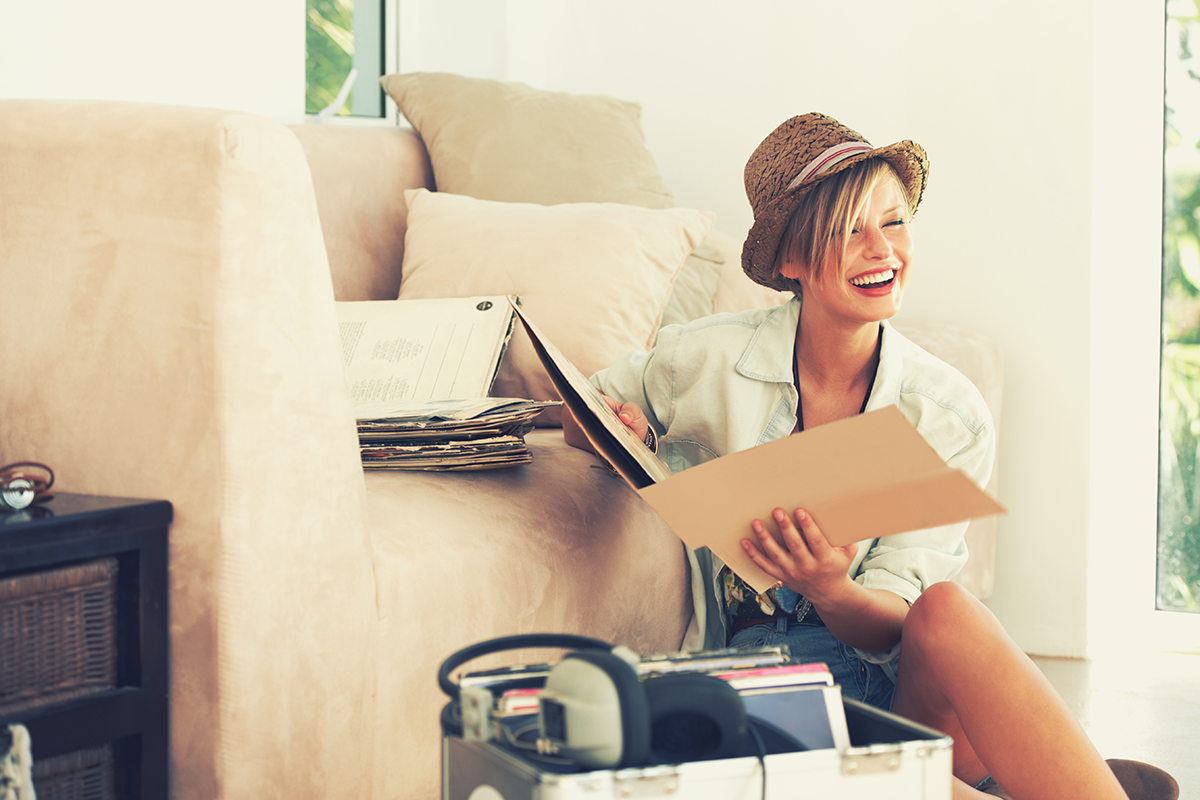 A beautiful young woman laughing while sitting and holding a record
