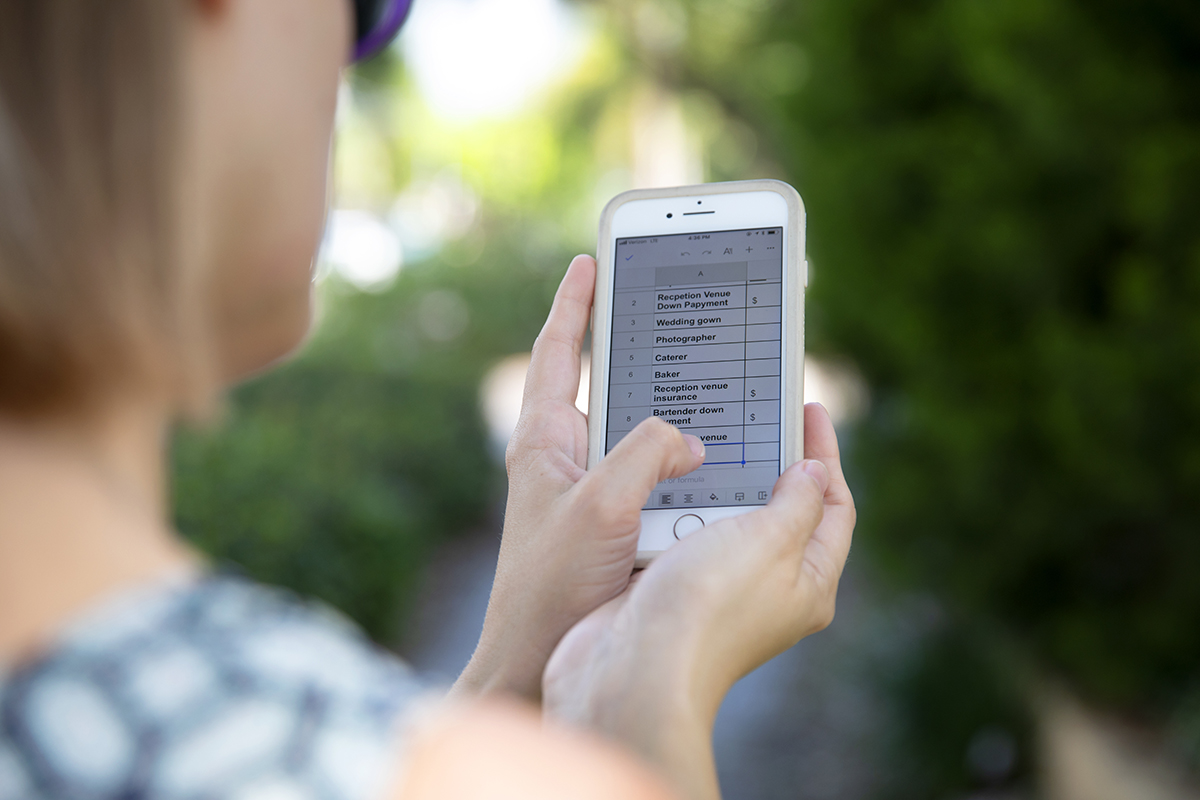 A woman looks at google sheets on her iPhone.
