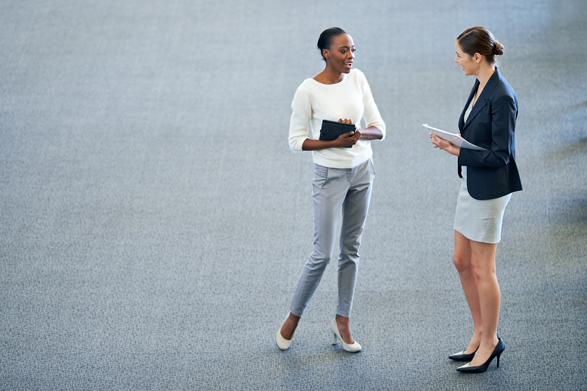 High angle shot of two coworkers stopping to chat at work
