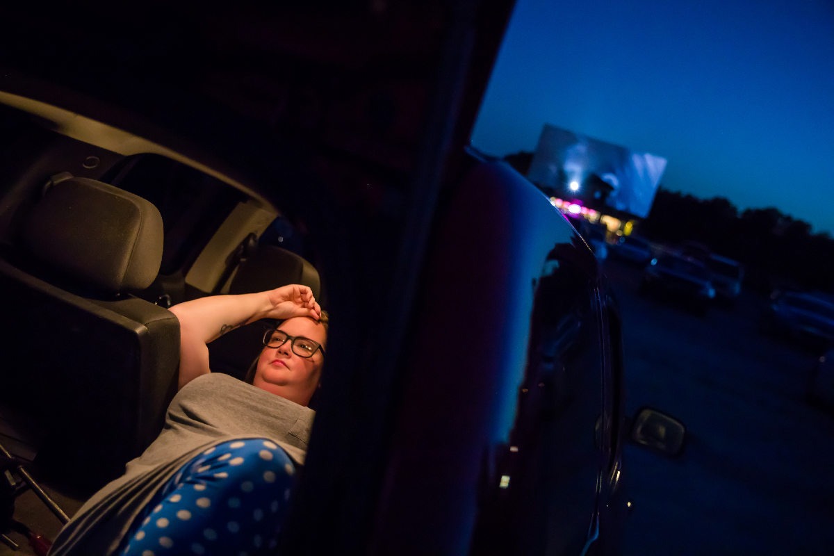 A woman watches a movie from her car.