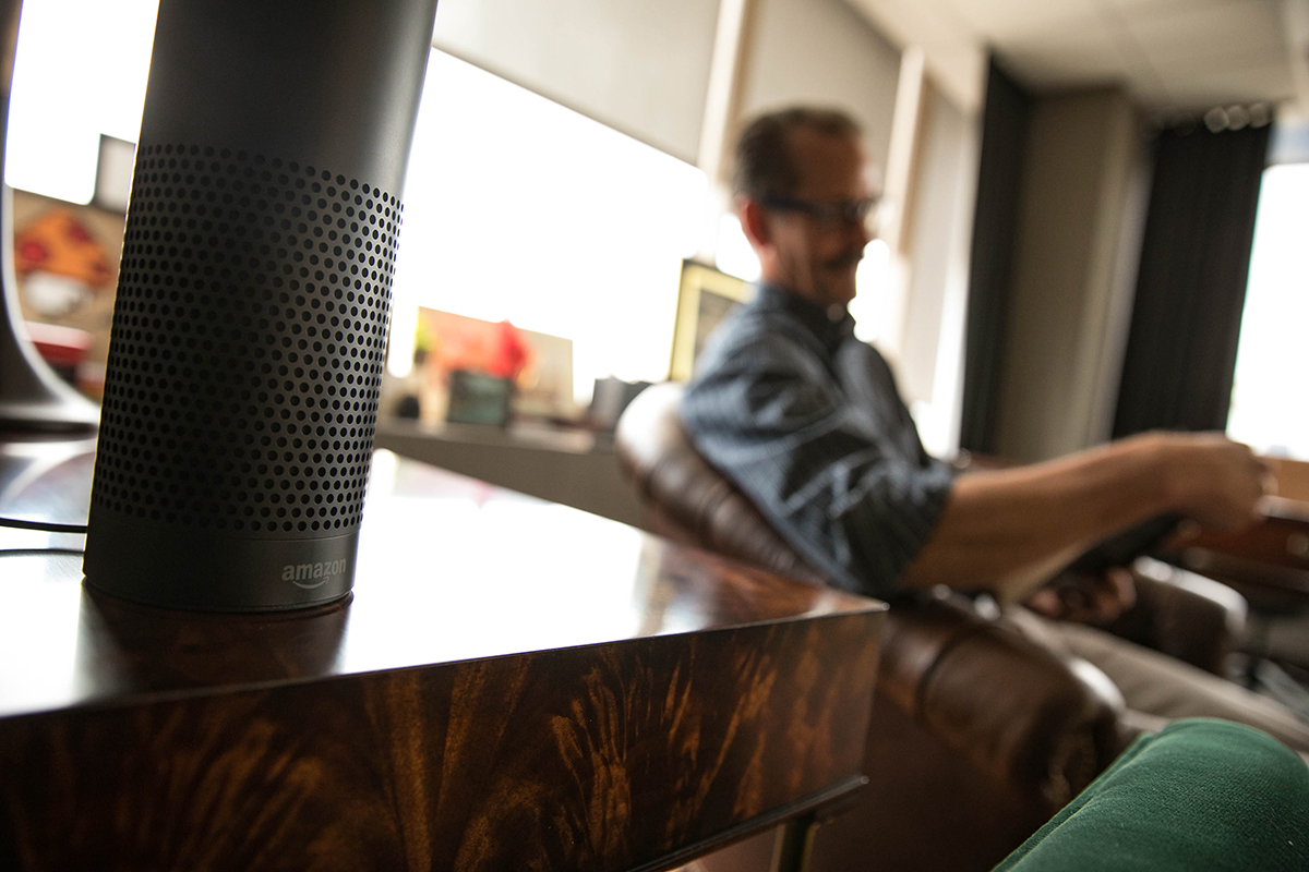 A man reads in a room with an Amazon Alexa digital assistant