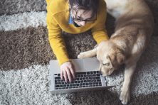 woman working at home on laptop with dog