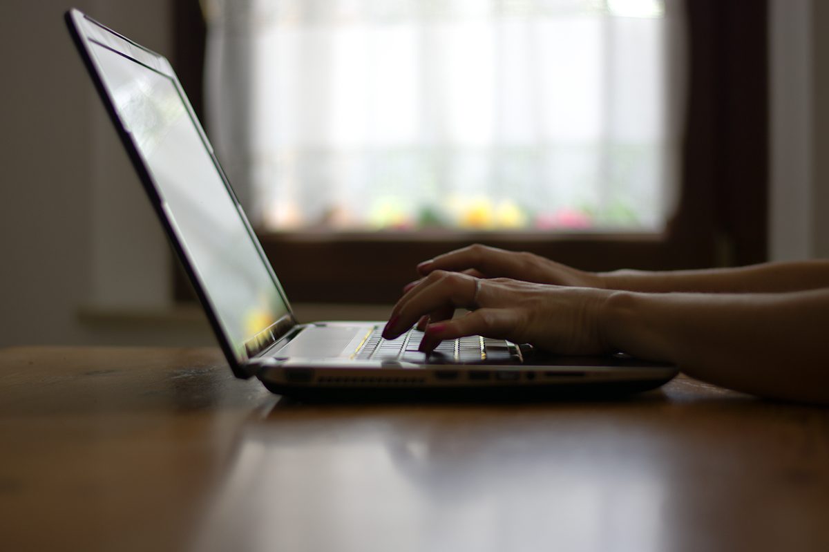 the hands of a woman type on a laptop on a table.