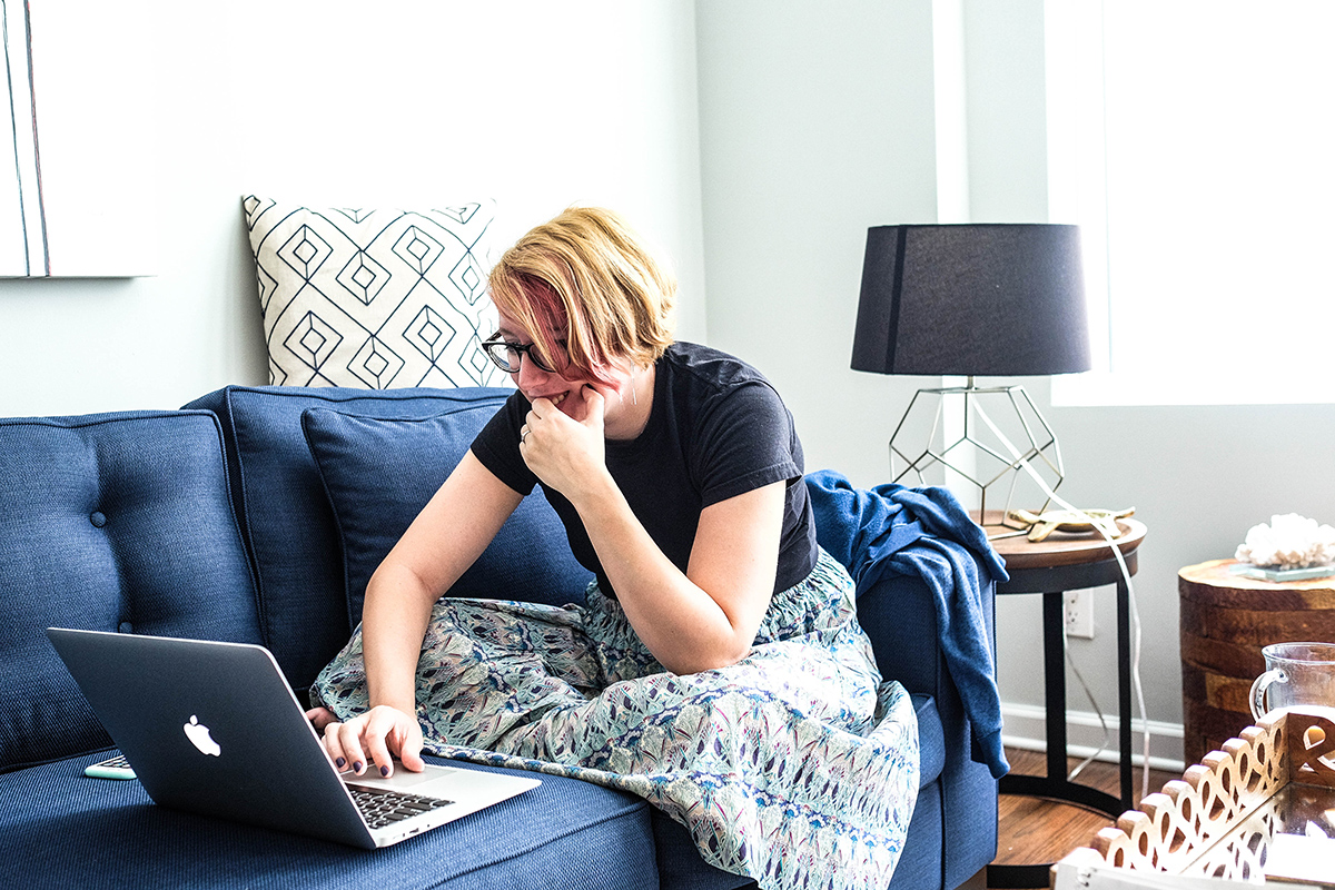 A woman using a laptop computer on a couch at home