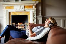 woman lying back on her sofa listening to music on headphones