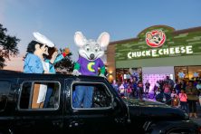 Chuck-e-cheese stands outside of a vehicle after a reopening of a Check E Cheese store.