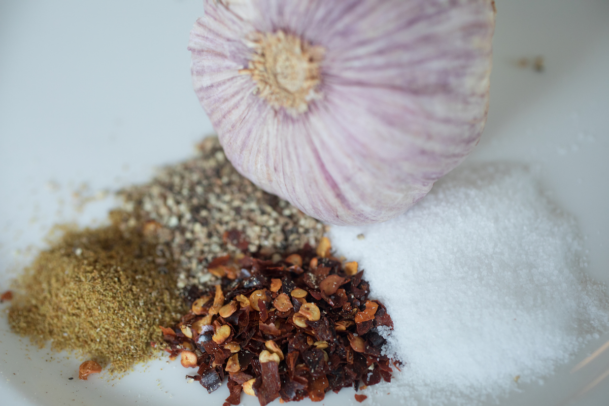 garlic, crushed red pepper, salt, cumin and pepper on a plate