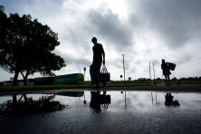 Two people walk through a rain puddle as they evacuate from the path of Hurricane Laura. The two people are photographed as a silhouette.