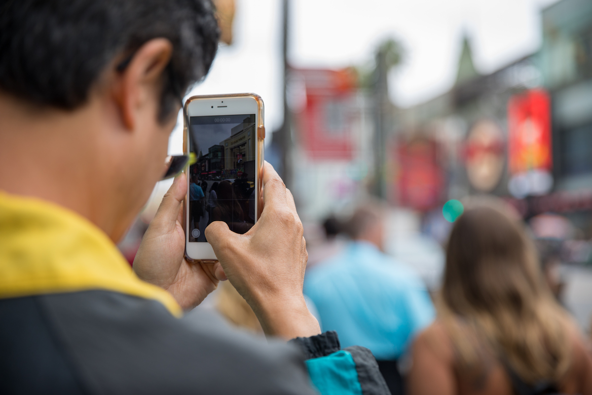 A man uses his smart phone to capture the scene before him.