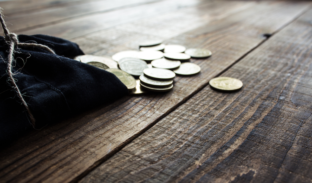 pouch of gold coins on wooden floors.