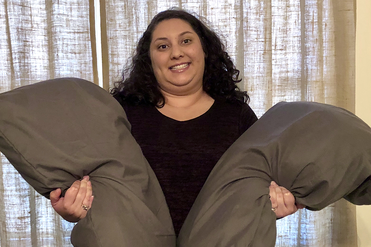 A smiling woman holds two pillows