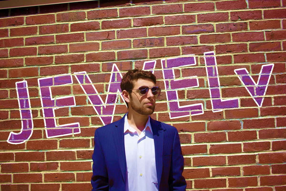 A businessman stands in front of a brick wall.