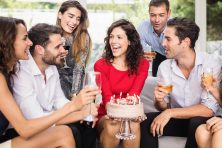 A woman celebrates her birthday surrounded by a group of friends.