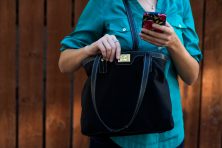 Woman holding her purse as she checks her phone.