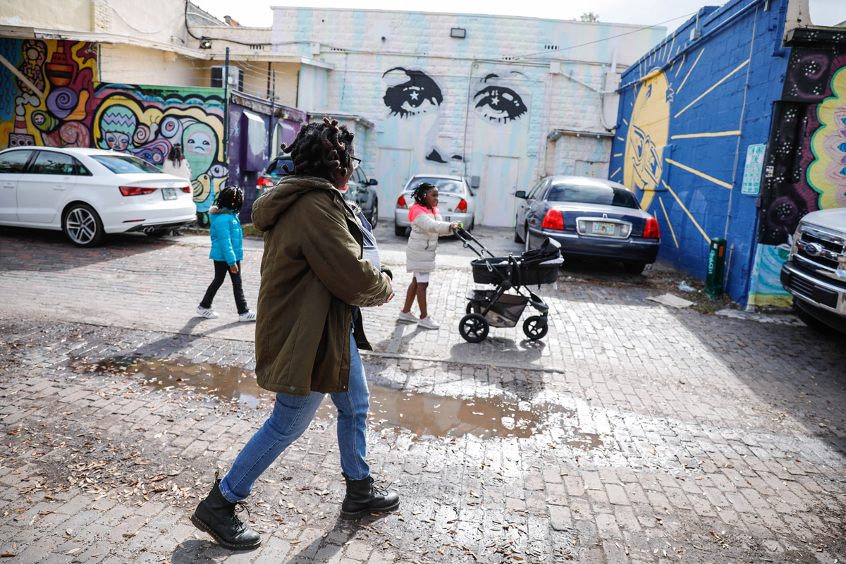 A mother walks through downtown St. Petersburg to look at murals with her daughters.
