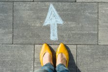 Female feet with arrow painted on the asphalt