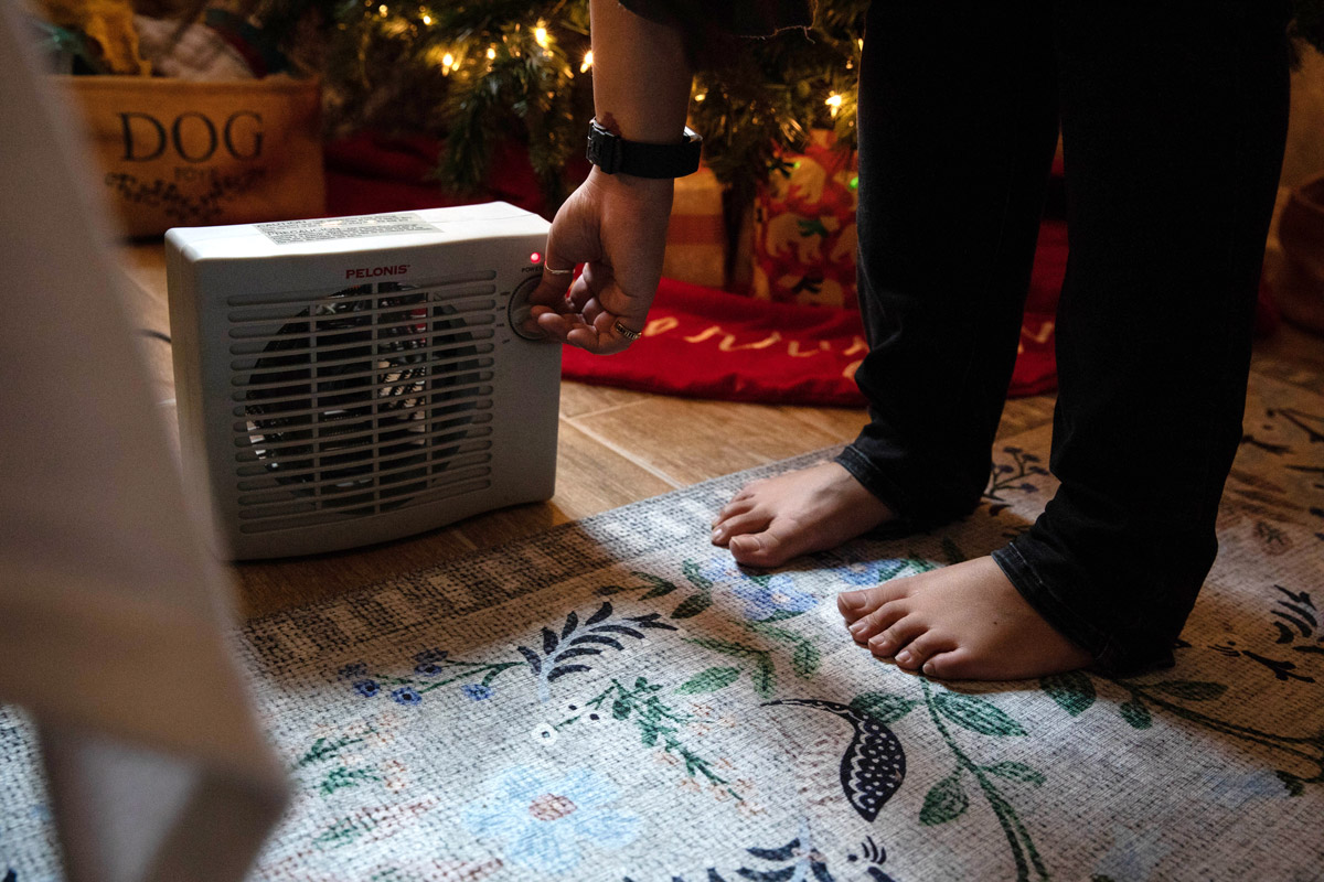 A woman turns on a space heater in her home.