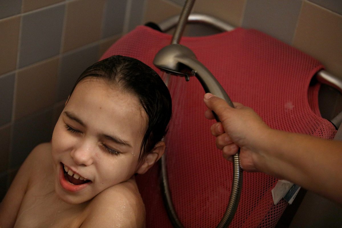 A daughter is bathed by her mother.