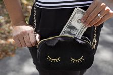 A woman puts cash money in her cute purse.
