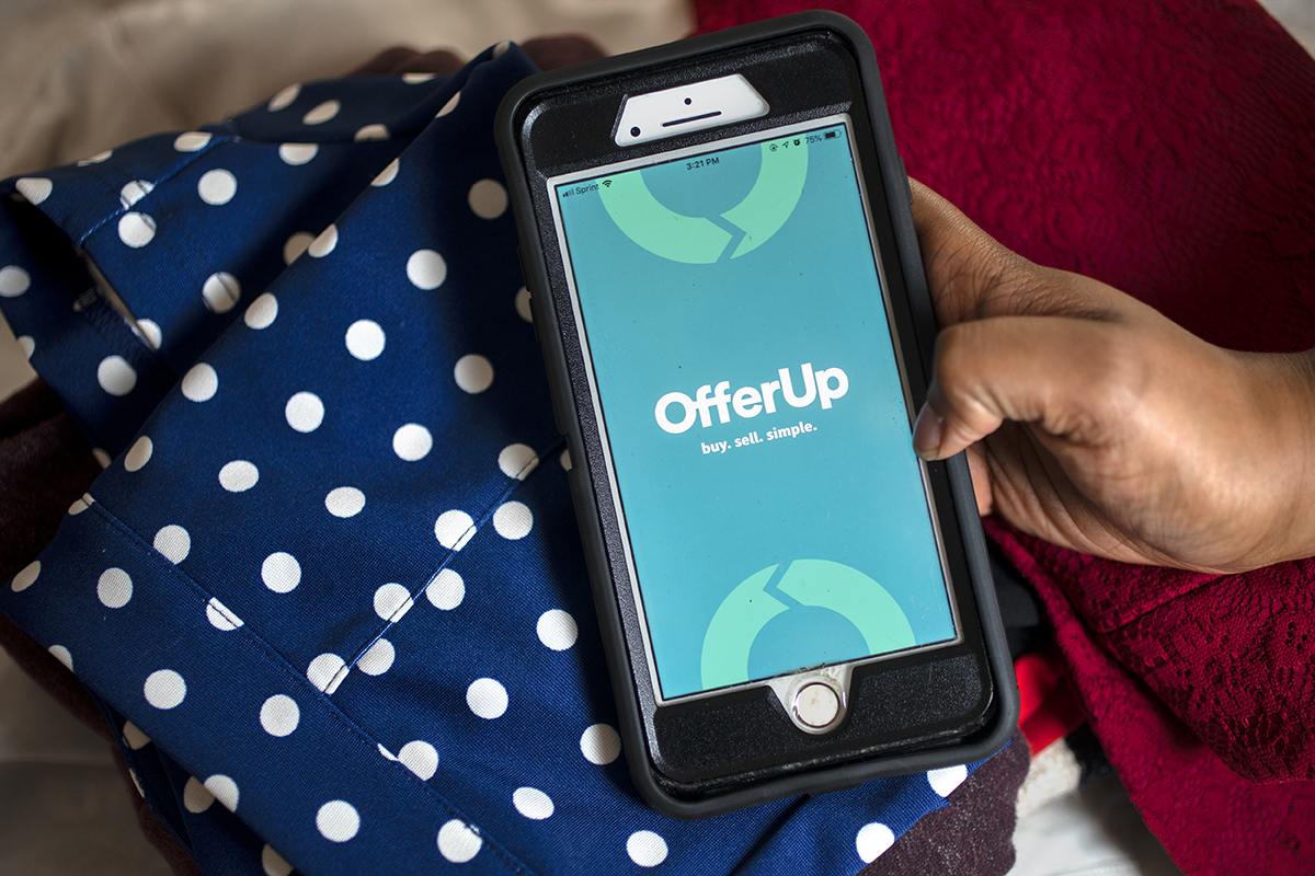 A woman shows the OfferUp app while selling clothes.