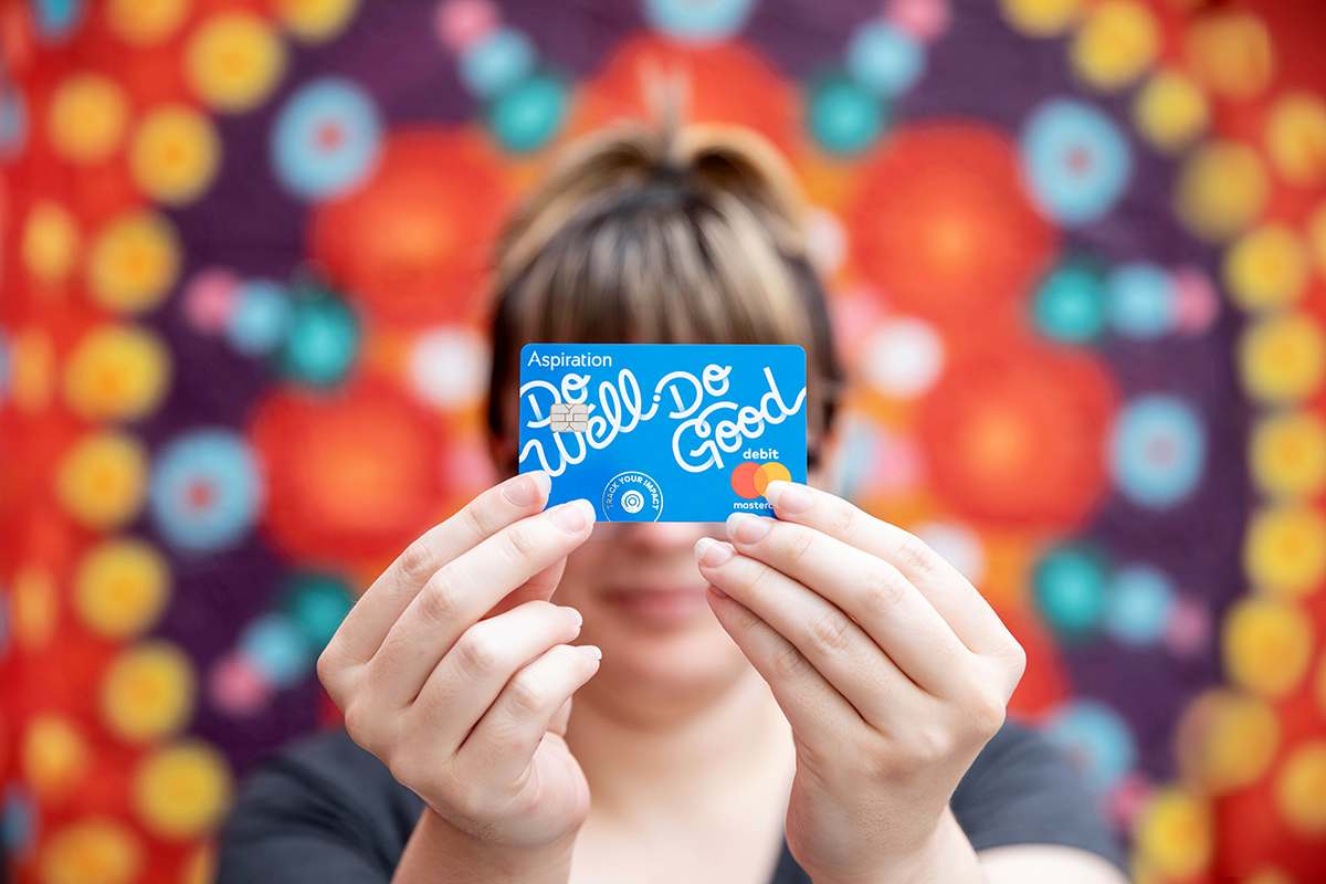 A woman holds an Aspiration debit card