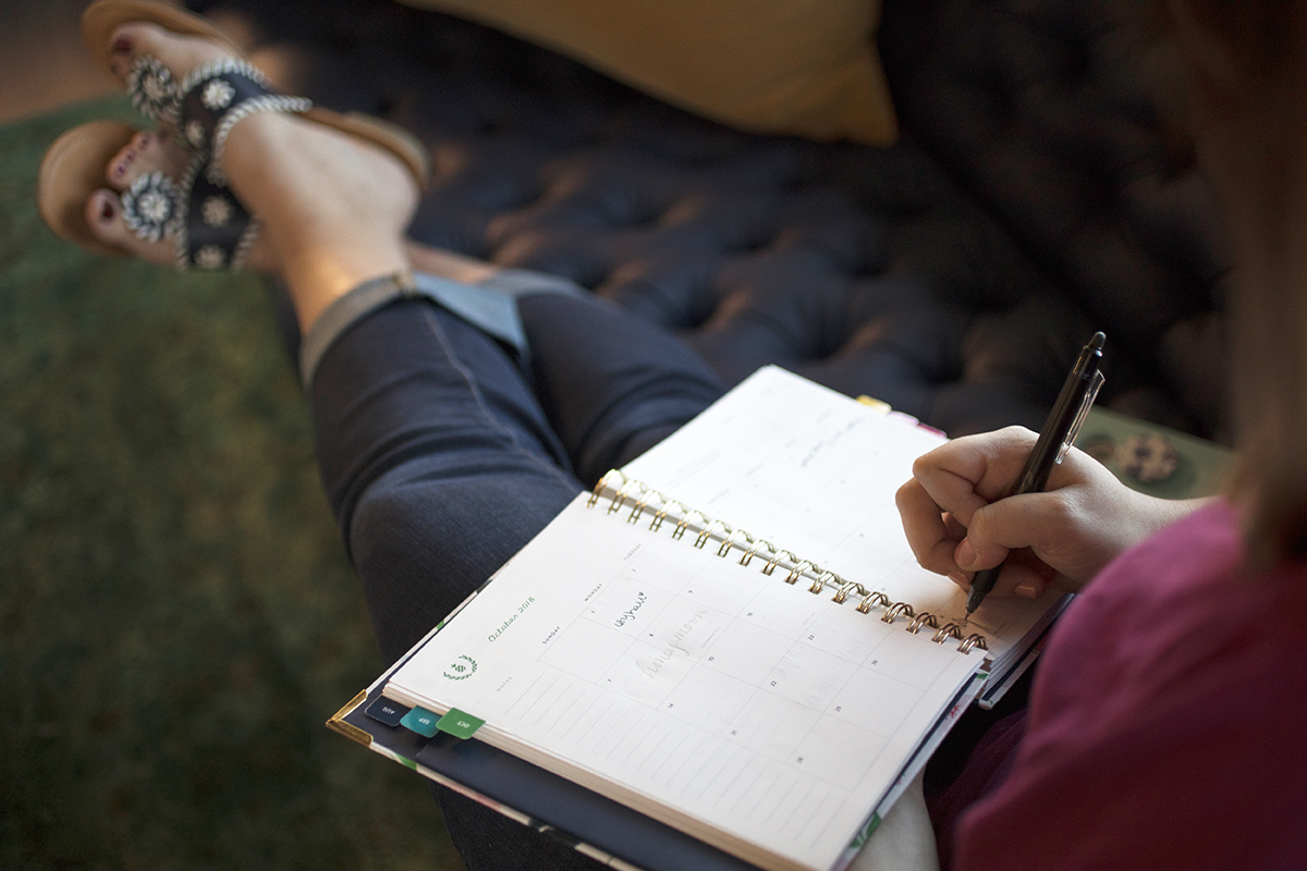 A woman writes a to do list in her planner