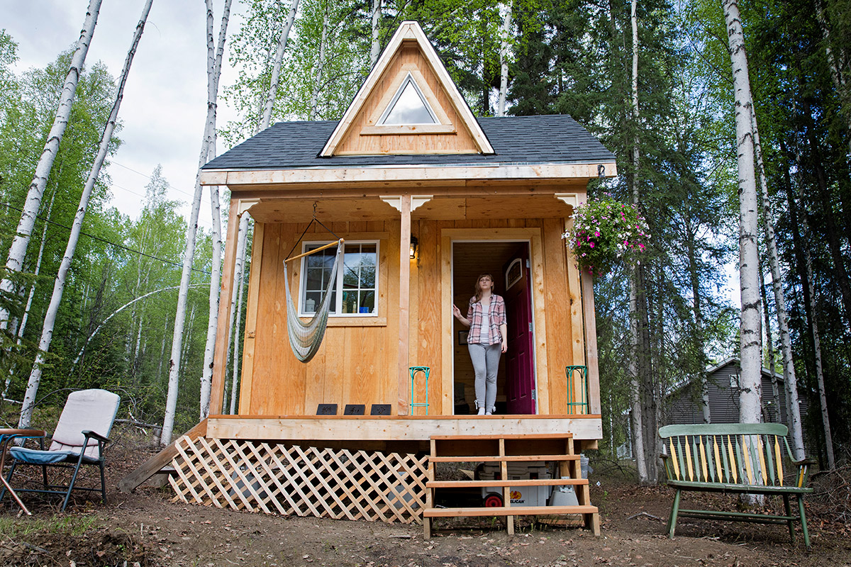 A woman stands in the doorway of her tiny home.
