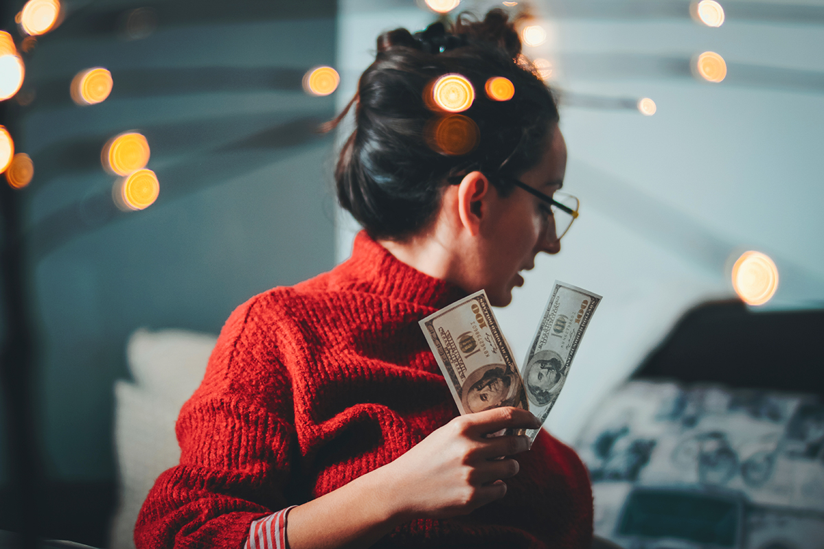 A young woman holds bills of money