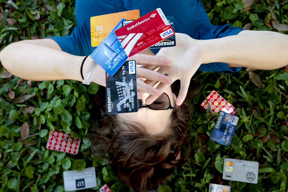 A woman throws credit cards in the air while lying down in the grass.